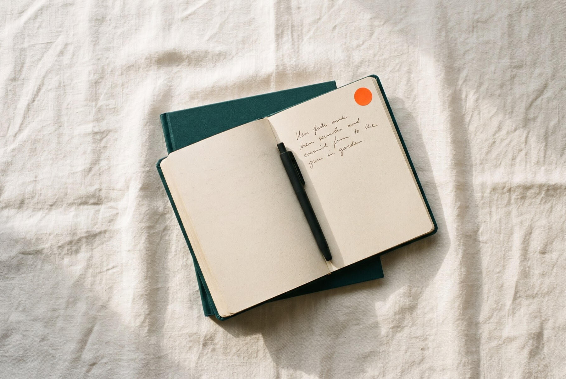 Cuaderno abierto con notas a mano y una pluma